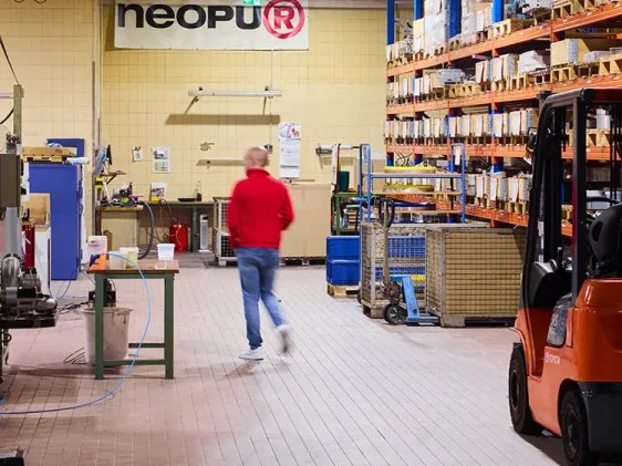 Blick in die Produktionshalle mit Hochregallager und Gabelstapler